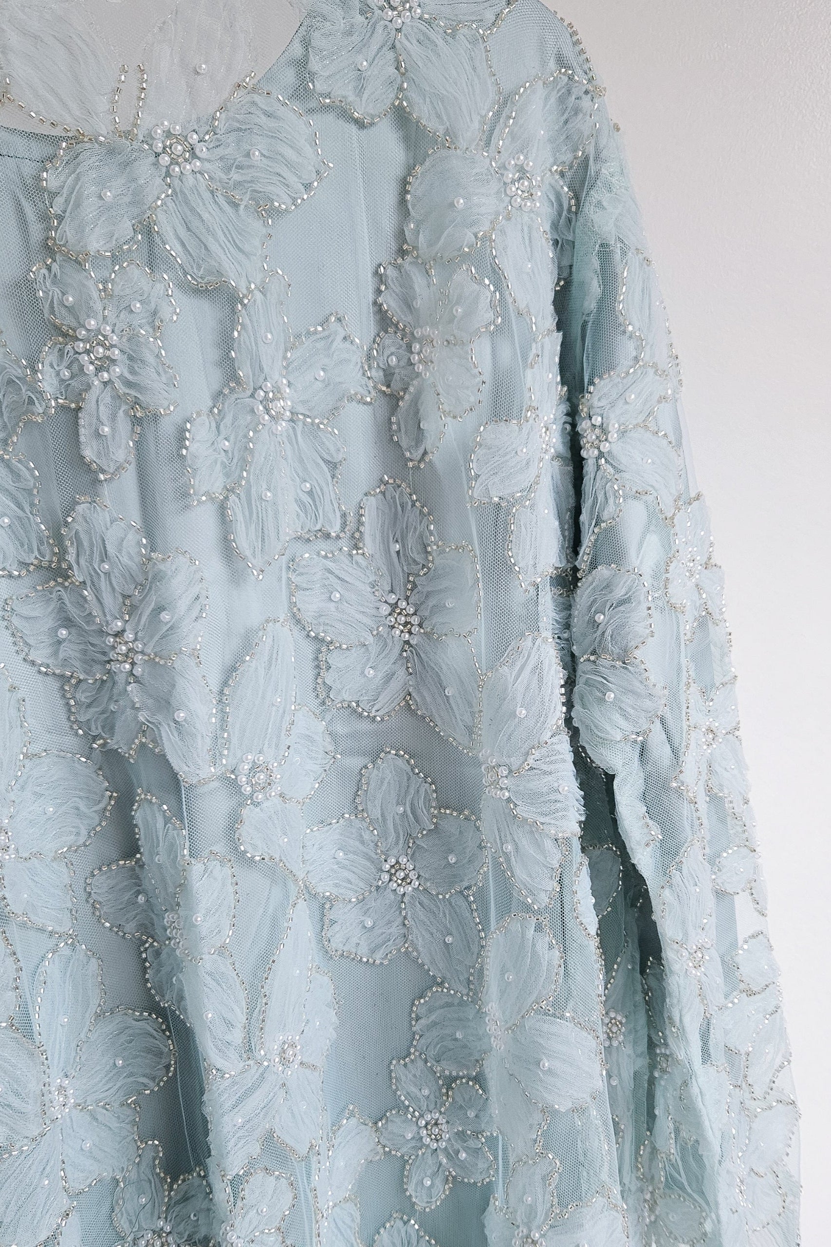 Light blue floral lace dress with intricate detailing on a white background